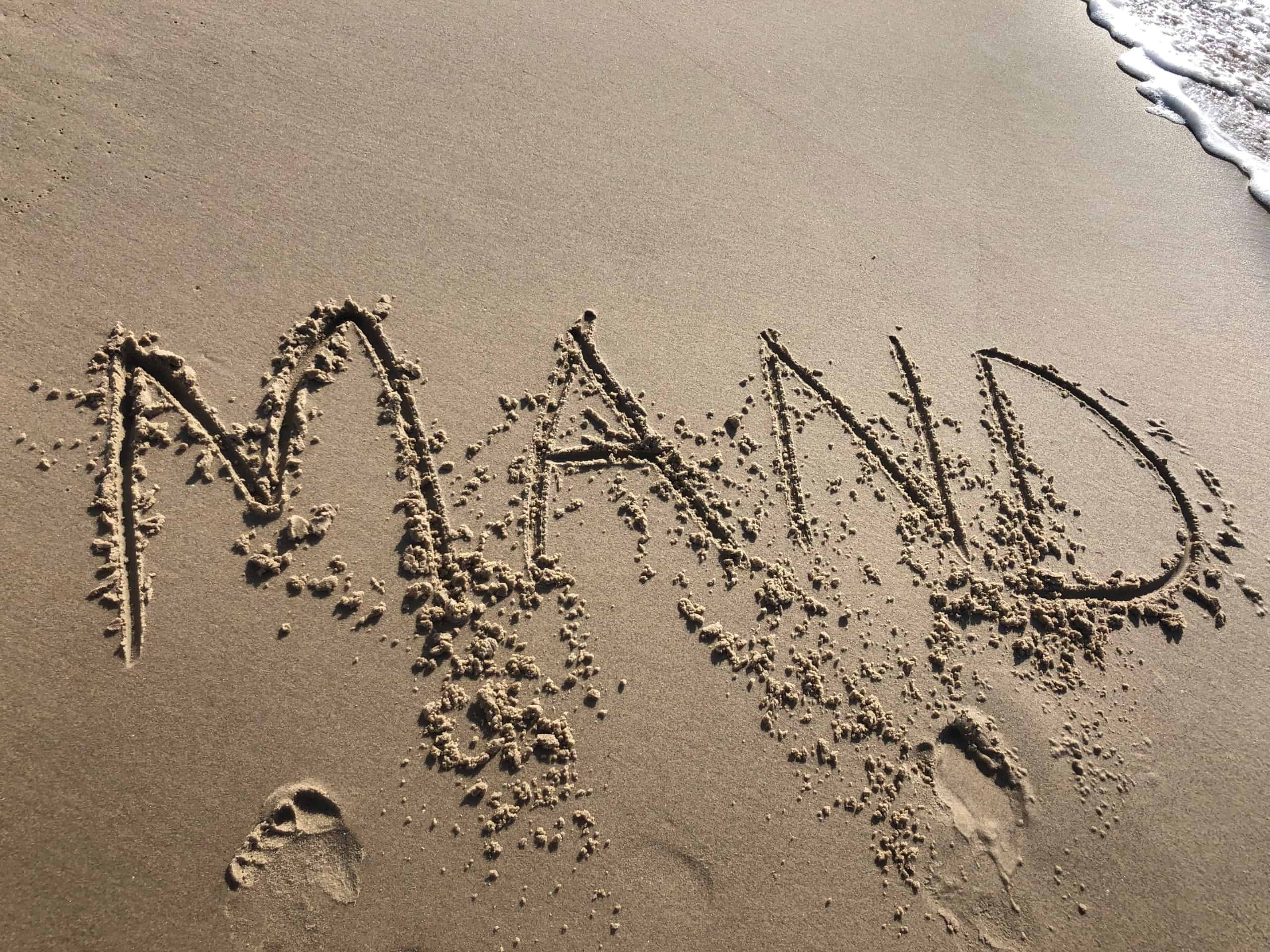 Mand skrevet i sandet på en strand